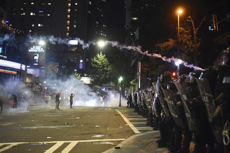 Varios manifestantes se encaran a policías antidisturbios durante las protestas ocurridas anoche por segundo día consecutivo en Charlotte. 