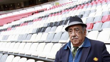 Melquiades Sánchez Orozco, la voz oficial del Estadio Azteca, posa con "Nachito", estatua localizada en uno de los asientos como monumento a los aficionados.