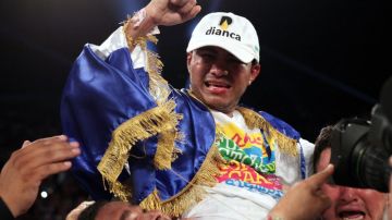 Román 'Chocolatito' González celebra envuelto en la bandera de su Nicaragua un nuevo campeonato mundial tras vencer al mexicano Carlos Cuadras.
