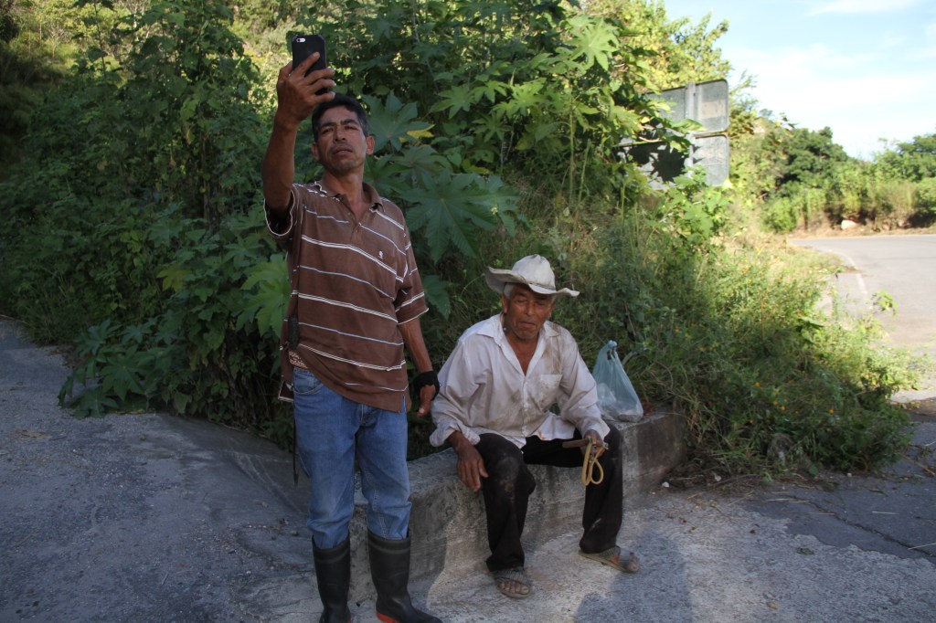 Ángel Morales López busca señal de internet mientras su padre espera que lo acompañe a pastorear los chivos.
