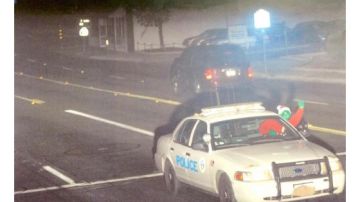 Un individuo disfrazado saluda a la cámara de tráfico tras saltarse un semáforo manejando un coche de la policía de San Bernardino.