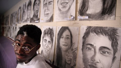 Phillip Sossou junto a algunos de los retratos que dibujó.