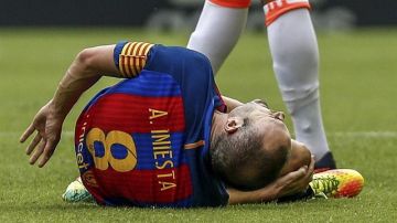 El centrocampista del FC Barcelona, Andrés Iniesta se duele de la entrada del jugador del Valencia Enzo Pérez.
