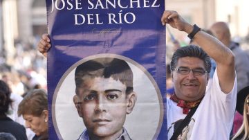 Un fiel sostiene un afiche de Jose Sanchez del Rio uno de los canonizados por el Papa.