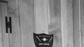 Jackie Robinson aparece en esta foto de 1956 mostrando algunos de sus trofeos en su casa de Brooklyn. Artefactos históricos suyos y de otras leyendas de los Dodgers serán exhibidos en Dodger Stadium.