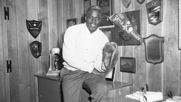 Jackie Robinson aparece en esta foto de 1956 mostrando algunos de sus trofeos en su casa de Brooklyn. Artefactos históricos suyos y de otras leyendas de los Dodgers serán exhibidos en Dodger Stadium.