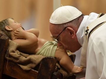 El papa Francisco besa una estatuilla de Jesús en la misa de víspera de Navidad.