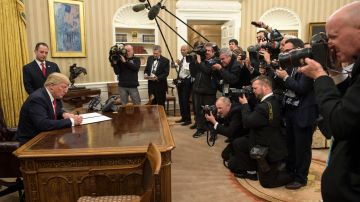Donald J. Trump (i) firma su primera orden ejecutiva como presidente, ordenando a las agencias federales que alivien la carga de Obamacare.
