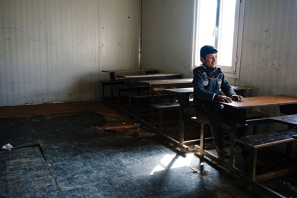 Un niño se sienta en pupitre en una escuela de Mosul.