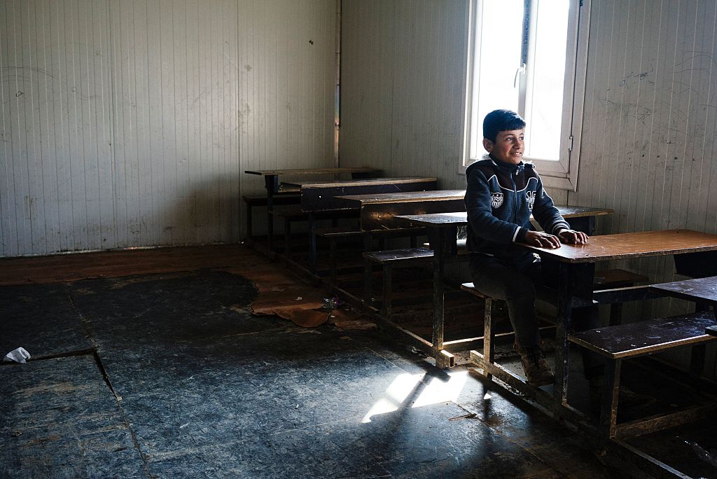 Un niño se sienta en pupitre en una escuela de Mosul. 