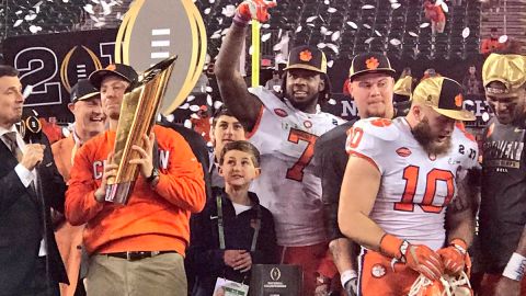 Entrenador y jugadores estrella de los Tigers de Clemson celebran con el trofeo de campeones del futbol americano colegial.