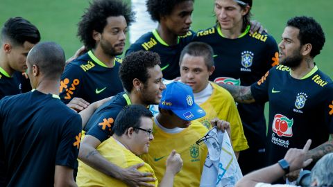 SAO022. SAO PAULO (BRASIL), 21/03/2017.- El jugador del seleccionado de fútbol de Brasil Neymar (ci), acompañado por sus compañeros, abraza a dos jóvenes admiradores con síndrome de Down durante una sesión de entrenamiento hoy, martes 21 de marzo de 2017, en el club Sao Paulo de la ciudad de Sao Paulo (Brasil). Brasil enfrentará a Uruguay el próximo jueves 23 de marzo en partido por las eliminatorias sudamericanas del Mundial de Rusia 2018. EFE/Sebastião Moreira