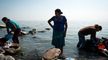 Mujeres y niños lavan en ropa en las aguas contaminadas del lago Chapala.