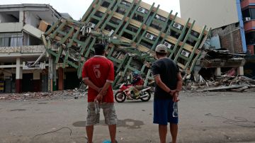 Dos hombres contemplan un edificio derrumbado por un sismo de alta magnitud en la ciudad de Portoviejo, en Ecuador.