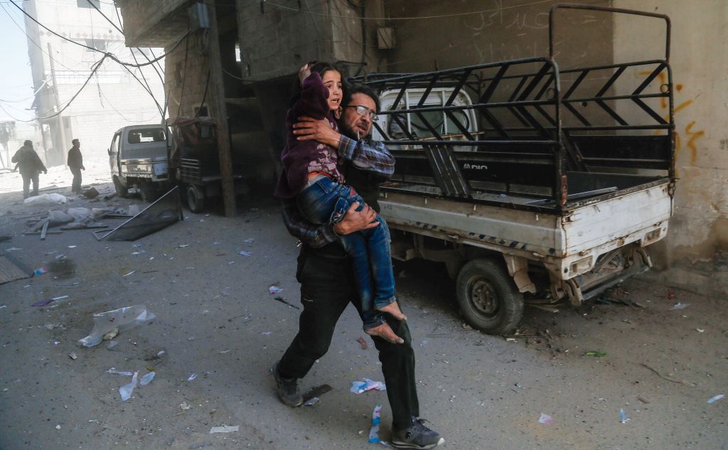 Un hombre sostiene a una niña mientras huyen tras un ataque aéreo oficial en las afueras de Damasco. ABDULMONAM EASSA / AFP / Getty Images