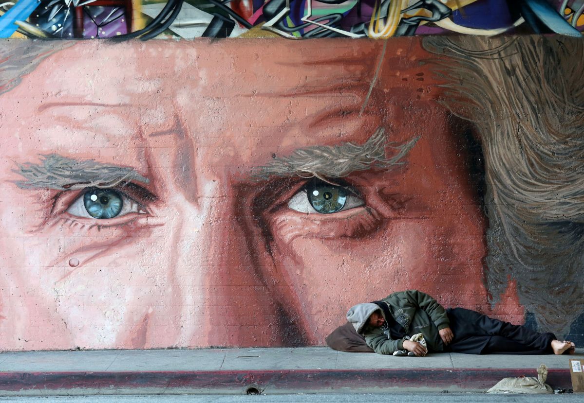 Un hombre sin hogar duerme en Glendale Blvd, bajo el puente de Sunset Blvd. en Los Angeles.