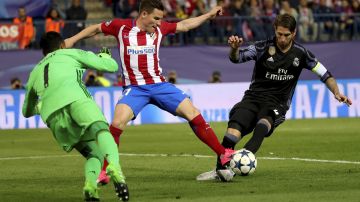 El delantero del Atlético de Madrid Kevin Gameiro (c) pelea un balón con Sergio Ramos.