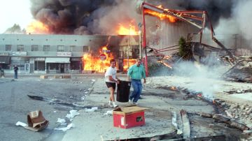 Dos personas llevan agua para apagar incendios en Los Ángeles durante los disturbios en 1992.