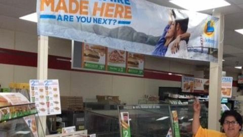 Estela Mora, cajera en la tienda 7-Eleven en Laguna Hills, apuntando al letrero señalando que allí fue donde se compró el boleto ganador.
