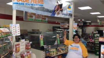 Estela Mora, cajera en la tienda 7-Eleven en Laguna Hills, apuntando al letrero señalando que allí fue donde se compró el boleto ganador.