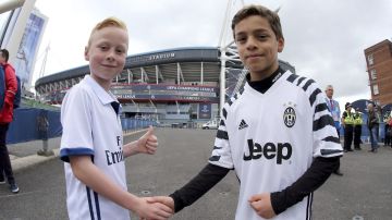 Dos jóvenes aficionados del Real Madrid y la Juventus estrechan sus manos