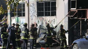 Bomberos tras el incendio en el almacén/vivienda de Oakland.