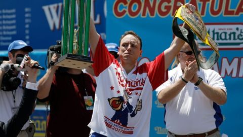 El estadounidense Joey Chestnut levanta el trofeo y el cinturón tras vencer en el Concurso anual masculino de perritos calientes de Nathan, celebrado en Coney Island, Nueva York.