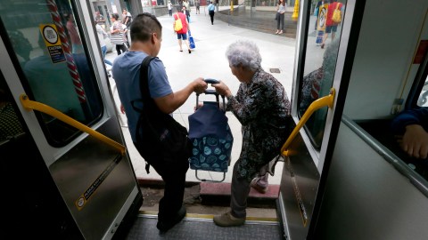 Un hombre ayuda a una anciana a bajar del autobús.