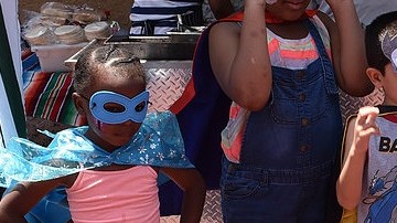 Alumnos son atuendo de superhéroe se divierten en una feria familiar.