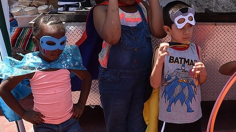 Alumnos son atuendo de superhéroe se divierten en una feria familiar.