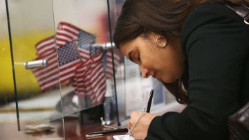 Una inmigrante firma su certificado de naturalización para convertirse en ciudadano en la oficina del USCIS.