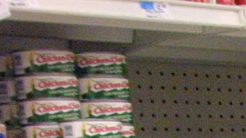 Una compradora revisa productos en el pasillo de abarrotes.