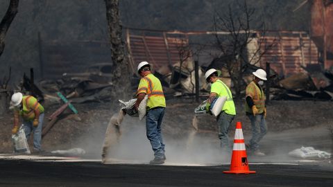 Trabajadores limpian residuos peligrosos en frente de un hogar calcinado en Glen Ellen.