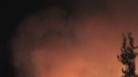 Un helicóptero lanza agua sobre las llamas.