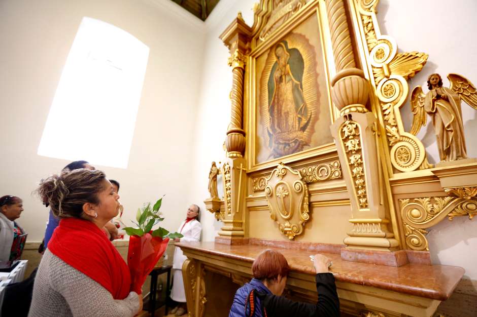 Feligreses oran frente a una imagen de la Virgen de Guadalupe dentro de la iglesia La Placita. (Aurelia Ventura/ La Opinion)