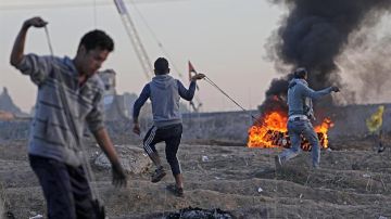 Manifestantes palestinos lanzan piedras contra las tropas israelíes