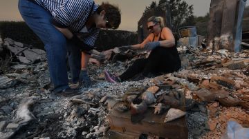 Miembros de la familia Reinhardt revisan los restos de su hogar después de que el incendio "Thomas" devastó al condado de Ventura.