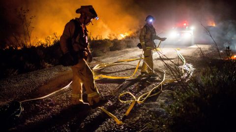 Bomberos trabajan para extinguir el incendio "Thomas" cerca de la autopista 101 en Ventura.