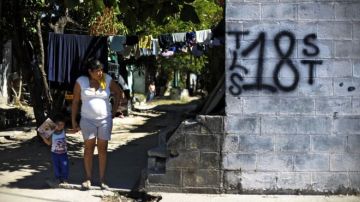 Mujer y niño junto a un grafiti del Barrio 18 en la colonia Valle del Sol en Apopa, El Salvador