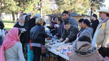 Voluntarios reparten comida a personas desamparadas en el parque Wells.