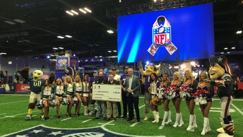 Momento en que la NFL anuncia la entrega de un millón de dólares a beneficio de veteranos de guerra. Atestiguan jugadores de los Minnesota Vikings y porristas de Eagles y Patriots.