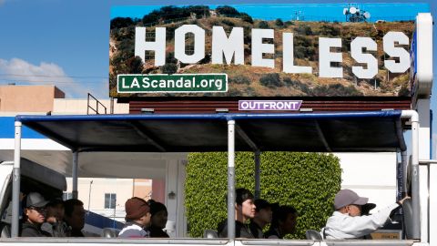 Turistas pasan al lado de una de las vallas publicitarias en Hollywood. (Aurelia Ventura/La Opinion)