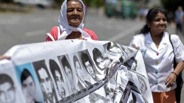 Mujeres sostienen una pancarta con retratos de personas desaparecidas durante la guerra civil del país centroamericano.
