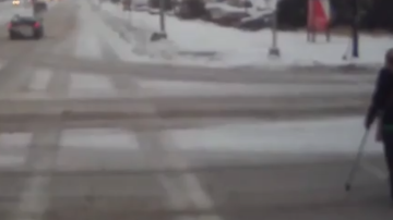 Una mujer en muletas cae al piso cruzando la carretera nevada y un conductor corre a salvarla.