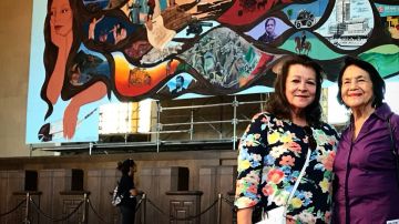 La artista Bárbara Carrasco posa en frente de su mural en Union Station, acompañada de la activista Dolores Huerta.