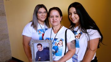 Maribel Grajeda con sus hijas Darlene y Mariyah Sancen sostiene la foto de su hijo Harvey Romero, cuyo crimen sigue sin resolverse. (Aurelia Ventura/La Opinion)