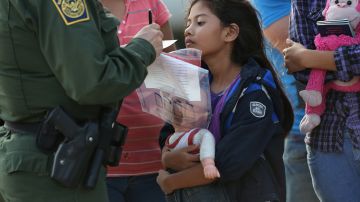 Inmigrante salvadoreña de 8 años junto al oficial de migraciones.