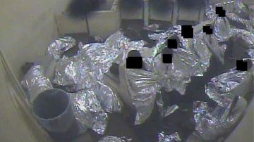 Un grupo de hombres arropados con mantas isotérmicas en una celda de la Patrulla Fronteriza.