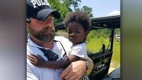 Policía rescatando a una niña en el bosque.