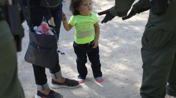 Agente de CBP toma en custodia a una niña y a su madre solicitantes de asilo.